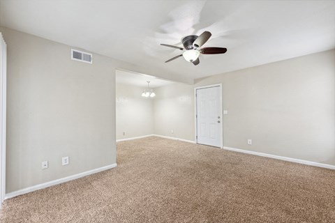 the spacious living room with ceiling fan and carpet